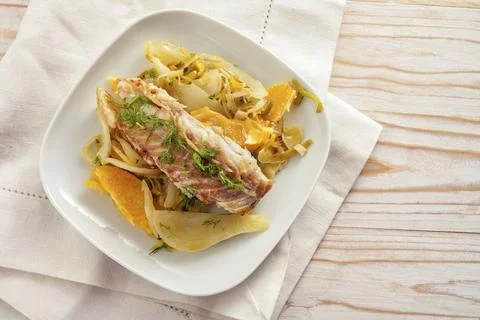 Cod fish fillet on fennel vegetable with orange slices and fennel green garnish Stock Photos