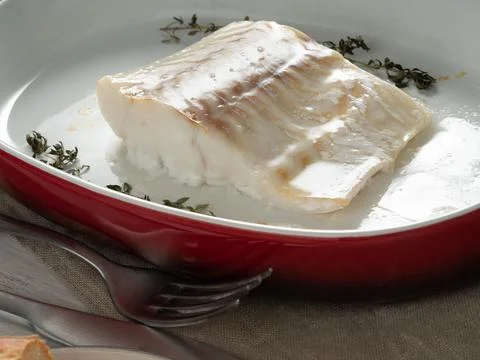 Cod fish fillet, freshly cooked in oven with thyme in a porcelain dish for Stock Photos