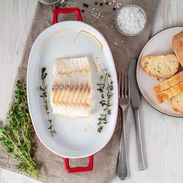 Cod fish fillet, freshly cooked in oven with thyme in a porcelain dish for Stock Photos
