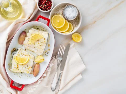Cod fish fillet, freshly cooked in oven with onion in red porcelain dish for Stock Photos