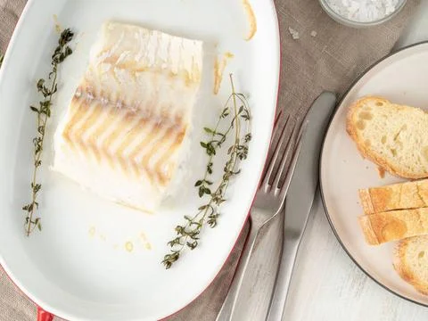 Cod fish fillet, freshly cooked in oven with thyme in a porcelain dish for... Stock Photos