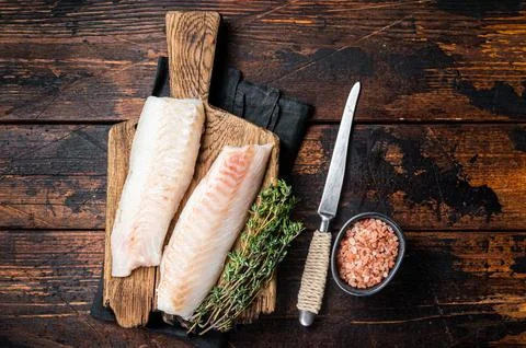 Cod fish fillets, raw codfish with thyme on wooden board. Wooden background.. 스톡 사진