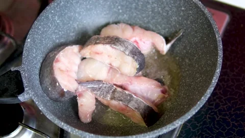 A cod fish steak frying in a frying pan close-up. Cooking fish in the hot oil at 库存影片 303522436