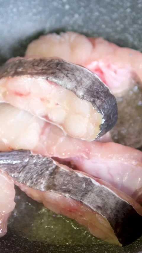 A cod fish steak frying in a frying pan close-up. Cooking fish in the hot oil at 库存影片 310169351