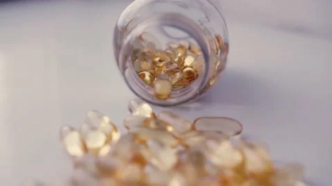 Cod liver oil omega 3 gel capsules spilling out of a bottle. Stock Footage 238428686