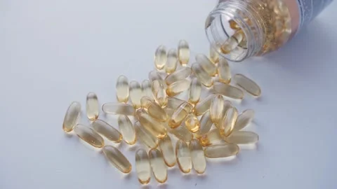 Cod liver oil omega 3 gel capsules spilling out of a bottle. Stock Footage 238430278