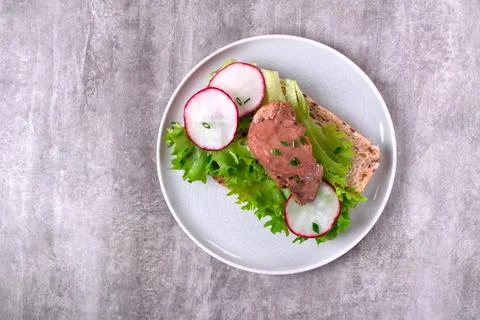 Cod liver served on bread slice with lettuce leaf and radish Foto stock