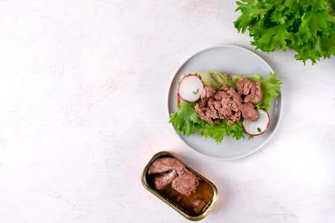 Cod liver served on bread slice with lettuce leaf and radish 스톡 사진