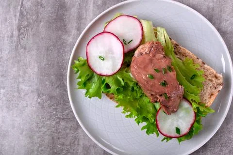 Cod liver served on bread slice with lettuce leaf and radish Foto stock