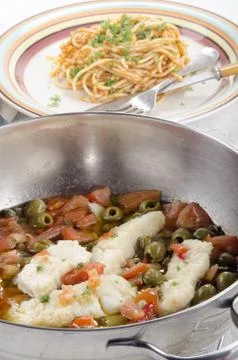 Cod with olive, caper, tomato and parsley Stock Photos