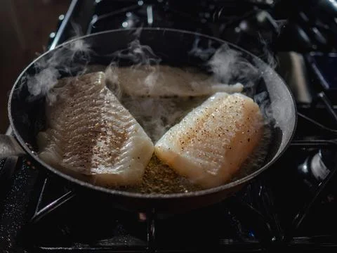 Cod in skillet being cooked in the hot pan Stock Photos