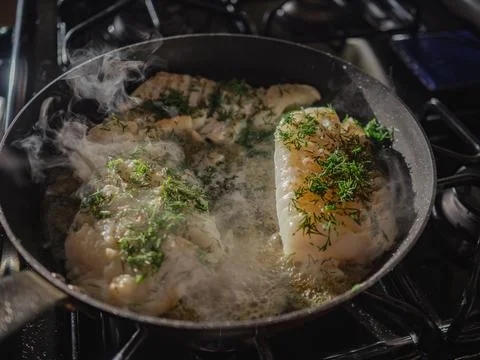 Cod in skillet being cooked in the hot pan Stock Photos