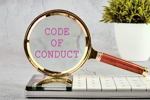 CODE OF CONDUCT words written through a magnifying glass standing on a calc.. Stock Photos