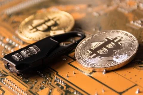 Code lock between gold and silver coins of bitcoins on the motherboard. Stock Photos