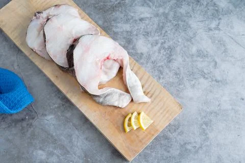 Codefish slices on marble bottom. Copy space. Fresh fish concept. Stock Photos