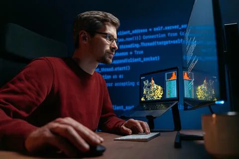 Coder in glasses works on a complex AI or data science problem late at night. Stock Photos
