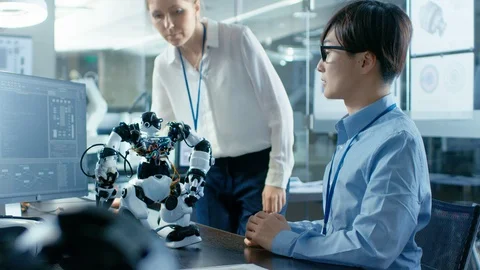 Coder Programmes Robot and Talks with Chief Engineer Stock Footage 85772272