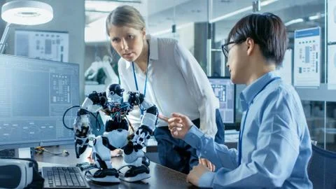 Coder Programmes Robot and Talks with Chief Engineer. They Work in a Lab Photos