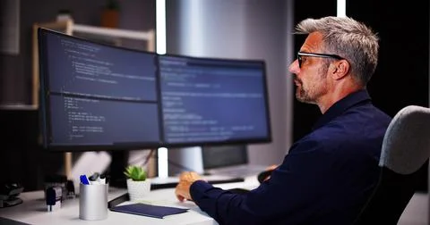 Coder Using Computer At Desk Foto stock