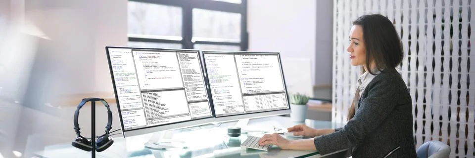 Coder Using Multiple Computer Screens Foto stock