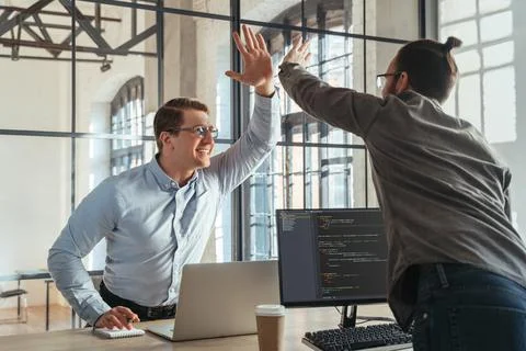 Coders giving high five to each other celebrating Stockfoto's