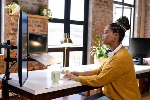 Coding on laptop at modern office desk, woman focused and determined Stock Photos