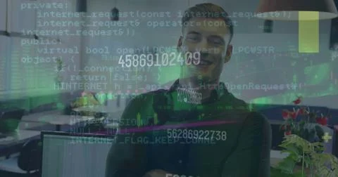 Coding man wearing dark top and headphones typing at office with monitors and Stock Photos