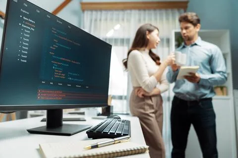 Coding screens on desk against developers drinking coffee standing. Postulate. 스톡 사진