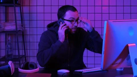 Coding specialist in casual with computer and talking by phone while coding Foto stock