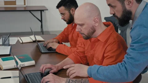 Coding Teacher Checking on Tattooed Male Convict Typing on Laptop in Prison Video stock 314055646
