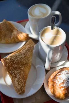 Coffe break at work. Top view on puff pastry and coffee cups on the table out Stock Photos