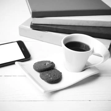 Coffe cup with cookie,phone and stack of book black and white co Foto stock