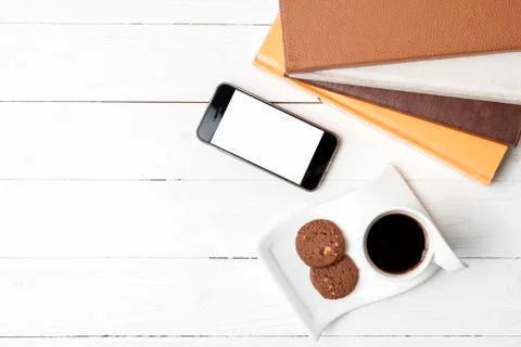 Coffe cup with cookie,phone and stack of book Fotos de archivo