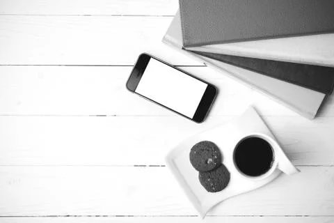 Coffe cup with cookie,phone and stack of book black and white co Fotos de archivo