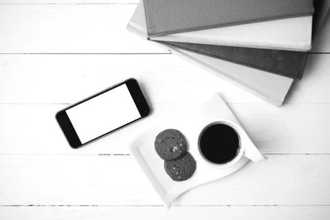 Coffe cup with cookie,phone and stack of book black and white co Fotos de archivo