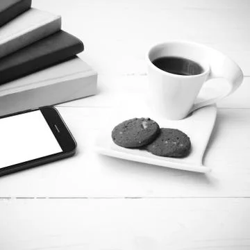 Coffe cup with cookie,phone and stack of book black and white co Fotos de archivo