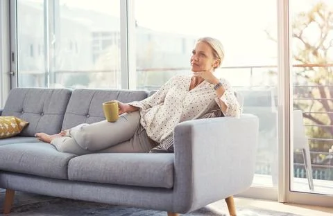 Coffee always help me to plan my day. a happy mature woman relaxing on the sofa Fotos de archivo