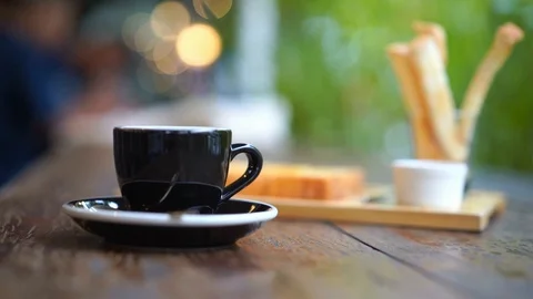 Coffee and bread on table with blurred green leaves and light bokeh background Stock Footage 93333124