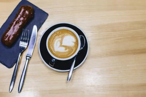Coffee and delicious chocolate eclair on a wooden table Stock Photos