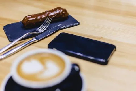 Coffee and delicious chocolate eclair on a wooden table Stock Photos
