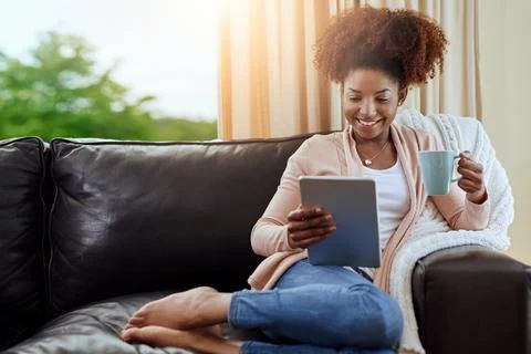 Coffee and a good e-book - perfection. a relaxed young woman using a digital Stock Photos