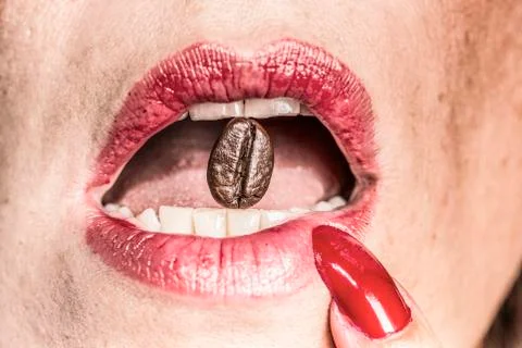 Coffee bean between red lips Stock-Fotos