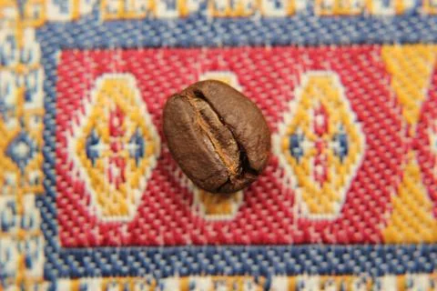 Coffee bean on the Eastern Turkish carpet. Eastern ornament macro Stock Photos