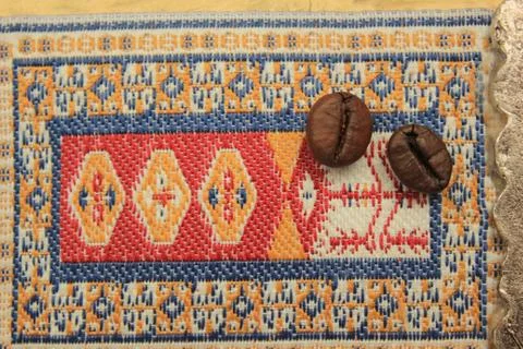 Coffee bean on the Eastern Turkish carpet. Eastern ornament macro. copy space Stock Photos