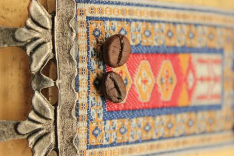 Coffee bean on the Eastern Turkish carpet. Eastern ornament macro. copy space Stock Photos