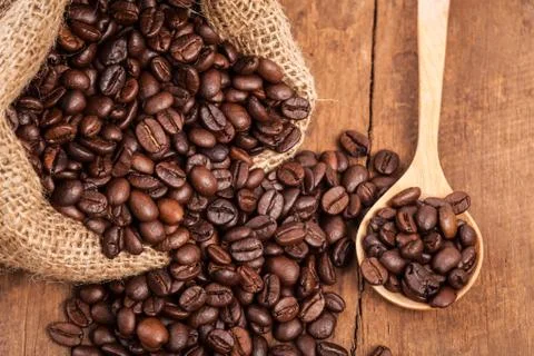 Coffee bean in sack on the wood table with wood spoon Stock Photos