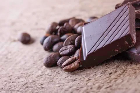 Coffee beans and chocolate closeup on a wooden board background Stock Photos