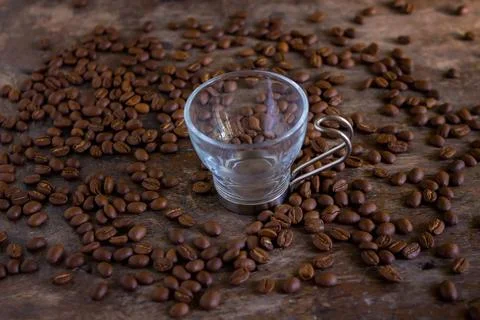 Coffee beans and empty cup on a table Stock Photos