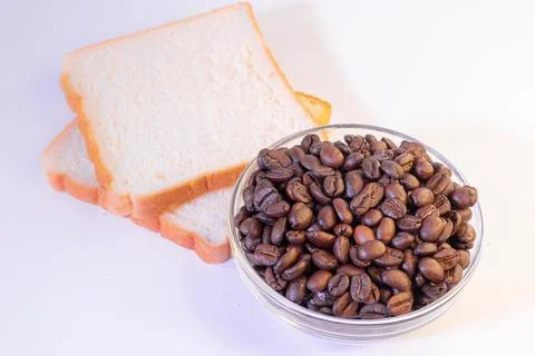 Coffee beans and slice of bread isolated on the white background. Stock Photos