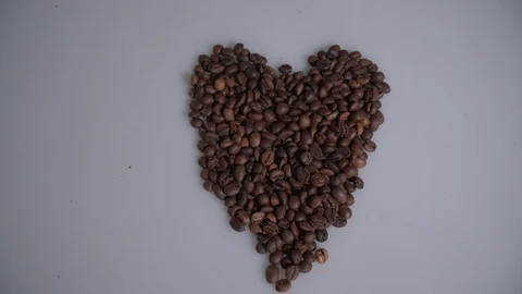 Coffee beans are collected in the shape of a heart on a white background. Vidéo 105753044
